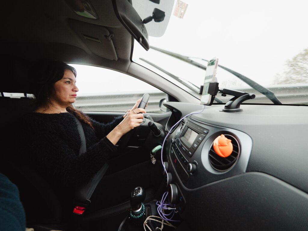 A woman is driving a car with a steering wheel and a dashboard